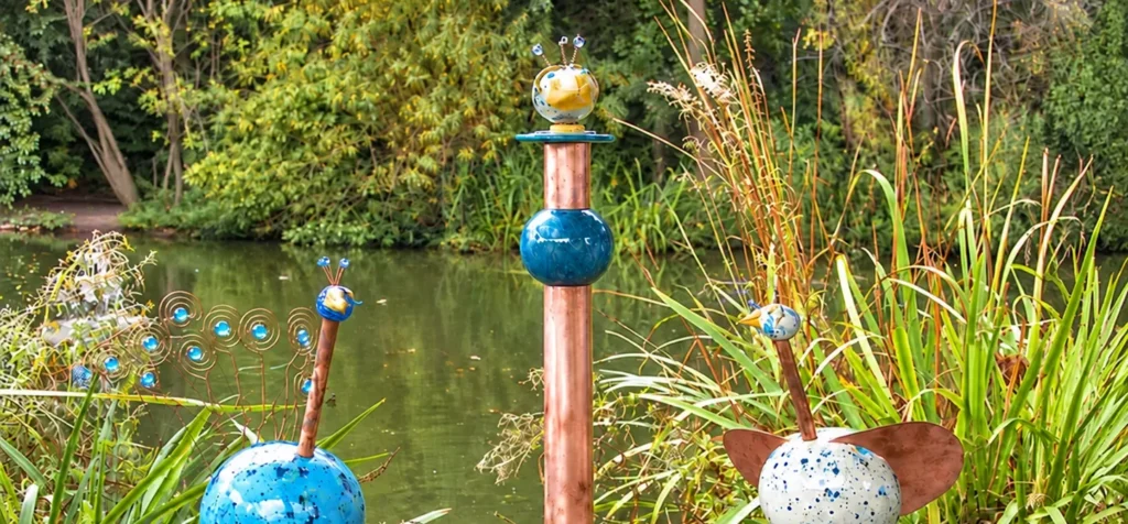 Mehrere unterschiedlich gestaltete Vogel-KERAMIKATUREN mit Kupferflügeln, Drahtdetails und hoher Stele tauschen Schwarmwissen aus..