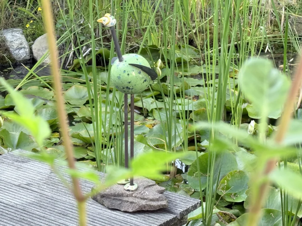 KERAMIKATUR zwischen Pflanzen am Teich im Garten des Ateliers in Wegberg.