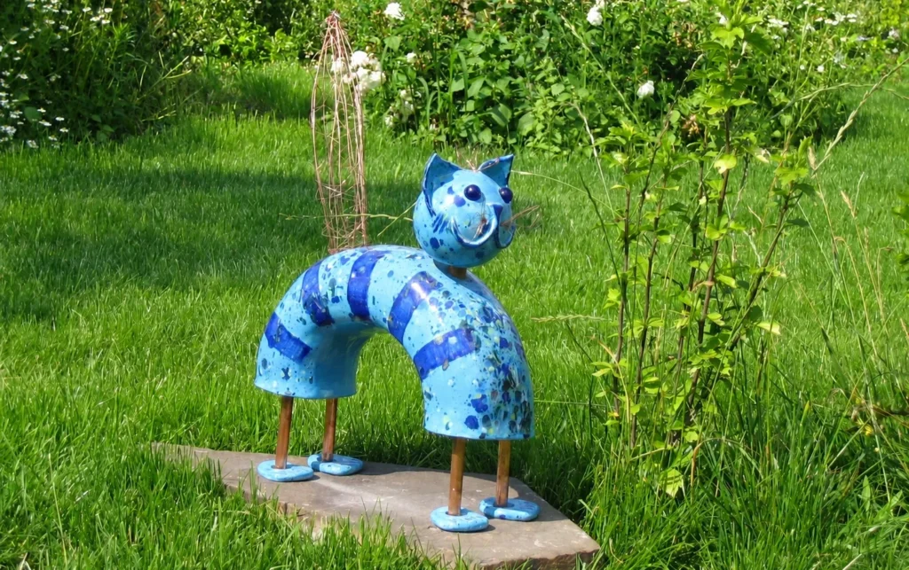 Blaue katzenartige KERAMIKATUR mit gebogenem keramischem Körper, Metallbeinen und drehbarem Kopf.