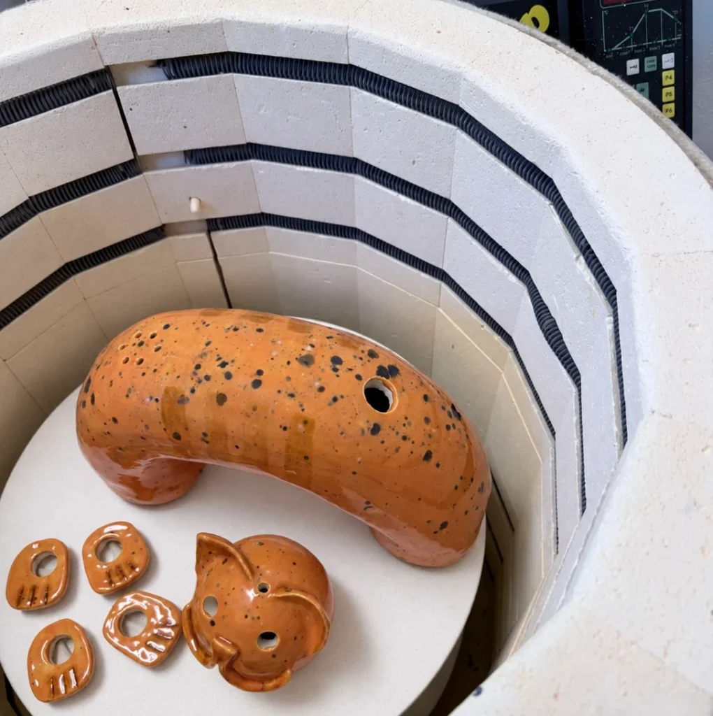Orange glasierte Keramikteile der KERAMIKATUR nach dem abgeschlossenen Glasurbrand im Brennofen.