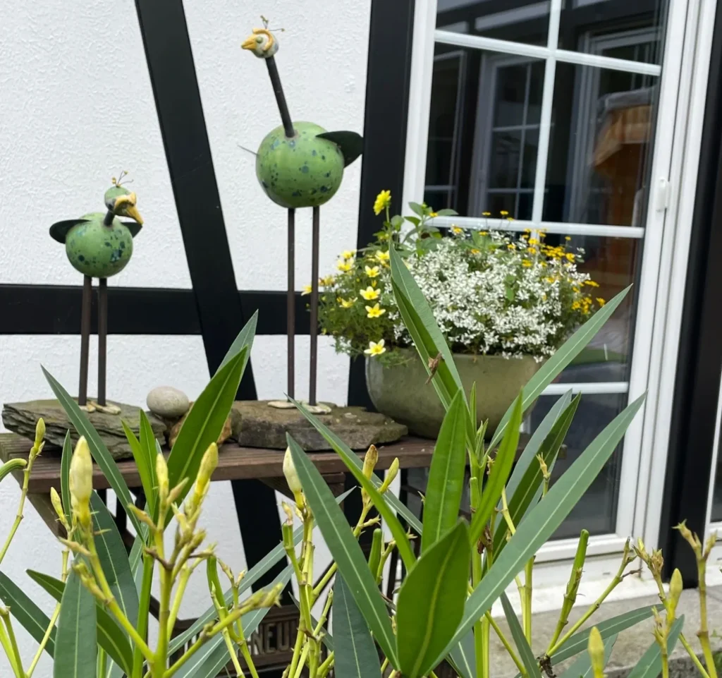 Zwei KERAMIKATUREN zwischen Pflanzen am Fachwerkhaus und Atelier in Wegberg.