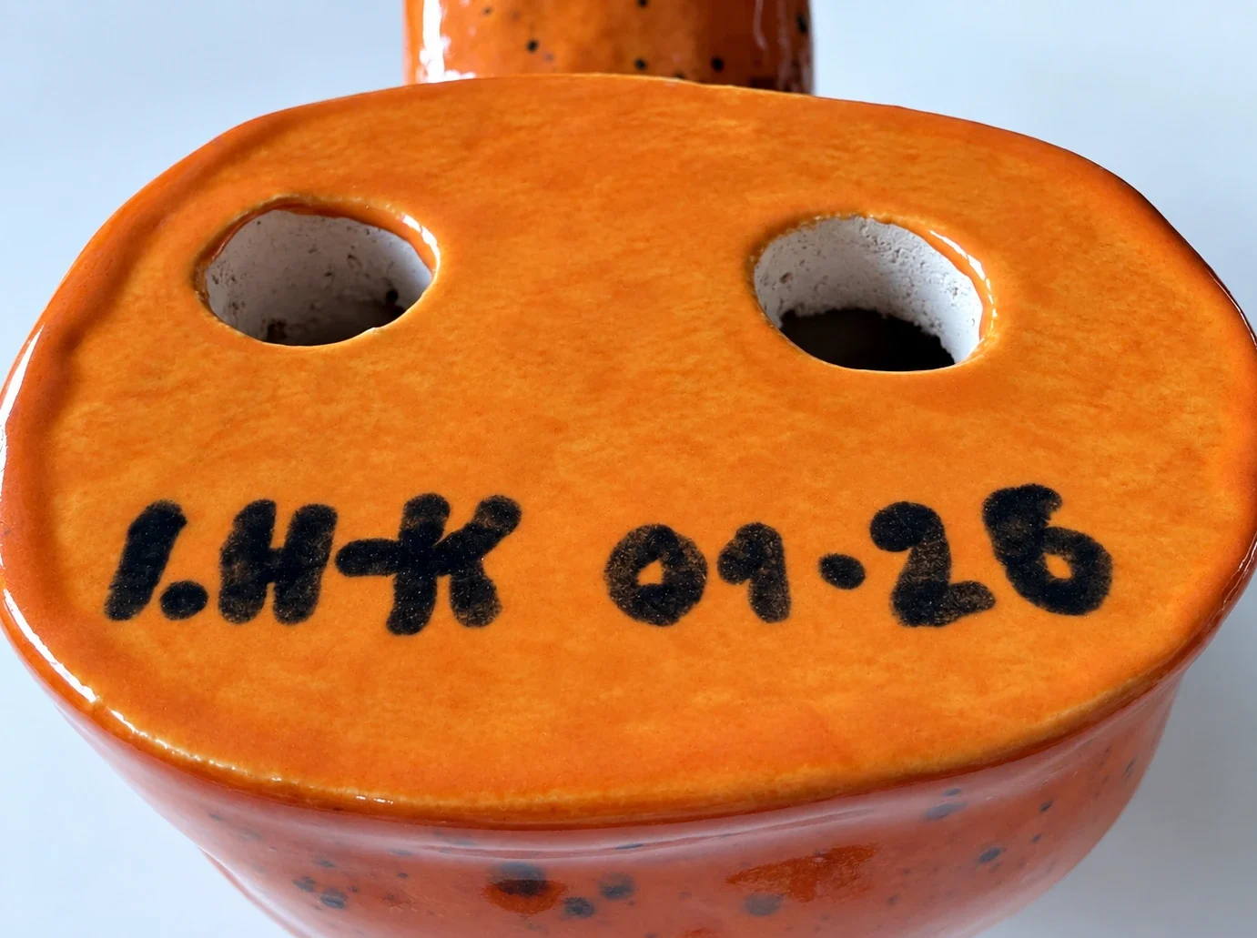 Signatur I.H-K 01-26 auf der Unterseite einer orange glasierten KERAMIKATUR.
